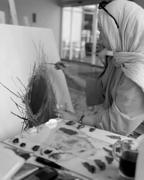 Nida Erdoğan painting the nest, her palette of oil colours beside the easel.